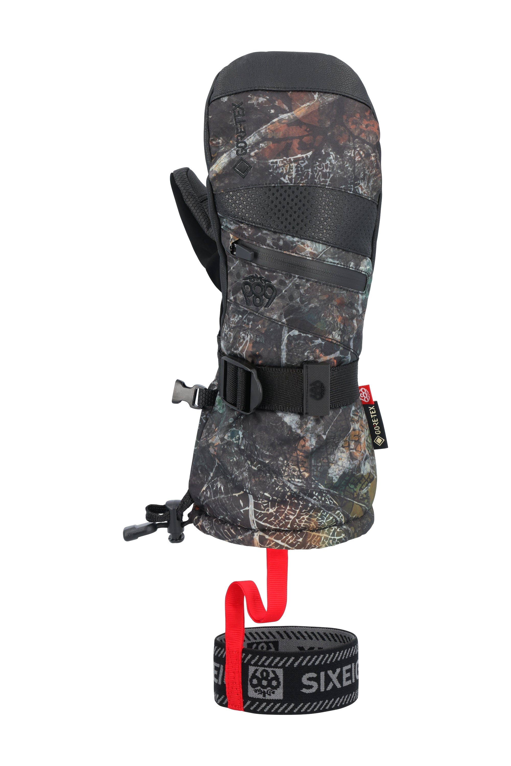The 686 brand offers a women's GORE-TEX SMARTY 3-in-1 gauntlet mitt in a camouflage pattern with black trim and accents, featuring a red pull tab on the wrist strap.