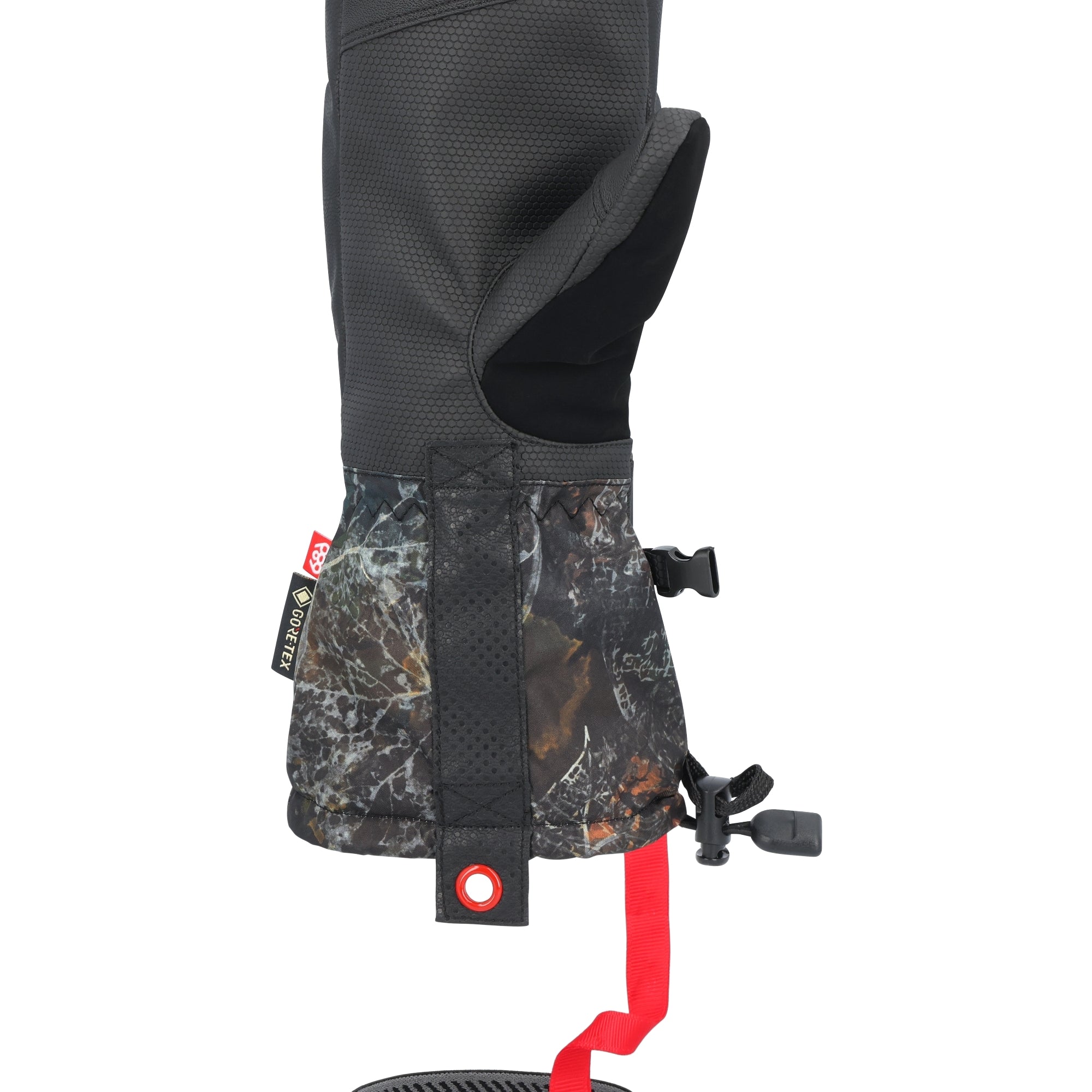 The 686 brand gauntlet mitt in this image features a black and gray camouflage pattern with an orange stripe down the back of the hand.