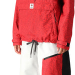 The 686 Women's Outline Shell Anorak 2025 is primarily red with a black pattern and has an adjustable drawcord at the waist.