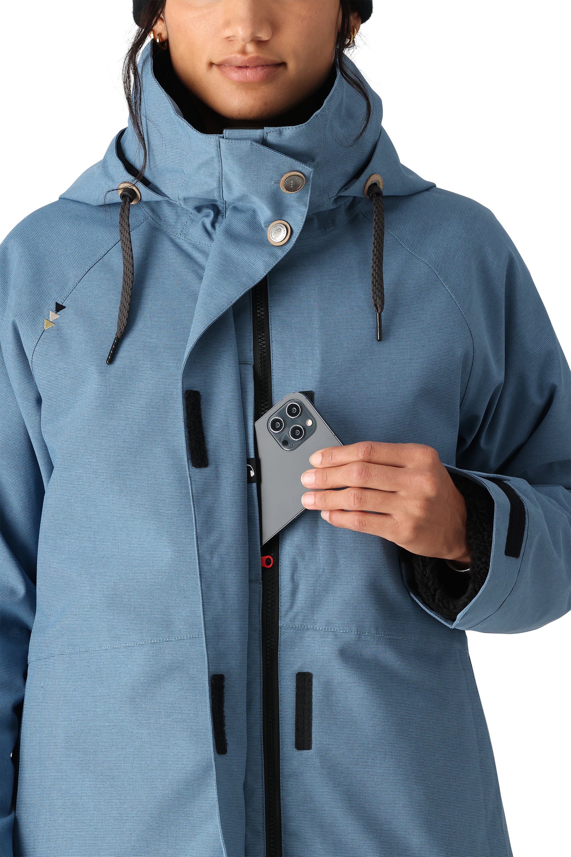 The 686 Women's SMARTY 3-in-1 Spellbound Jacket in this image is a light blue jacket with an insulated hood and black drawstrings.