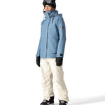 The 686 Women's SMARTY 2025 Spellbound jacket is light blue with a brown patch on one sleeve and a hood.