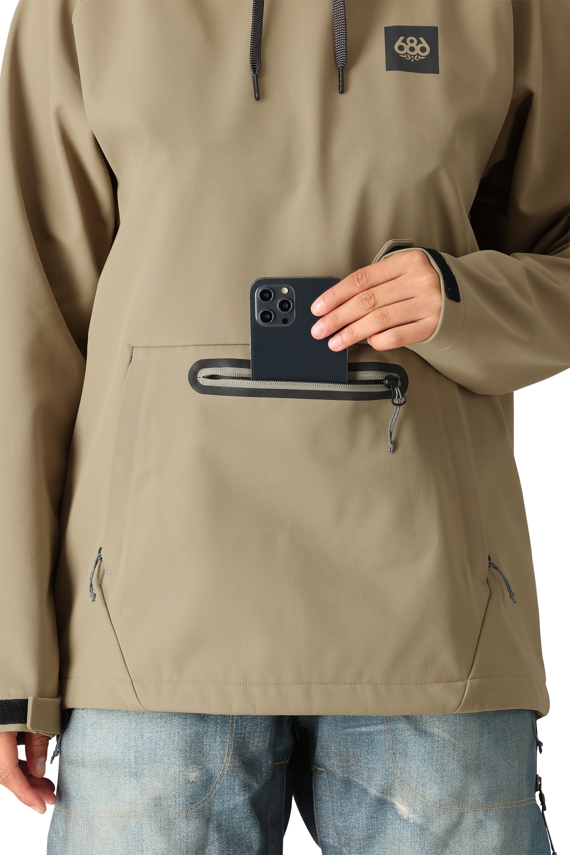 The 686 Women's Waterproof Hoody 2025 is shown in the image from the front view, with a tan color and a zippered pocket on the chest.