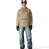 The 686 Women's Waterproof Hoody 2025 has a tan body with a black drawstring and logo on the left side of the chest.