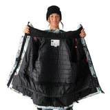 A black and white 686 snowboarding jacket with a colorful patterned lining is being held up by a woman wearing a matching beanie.