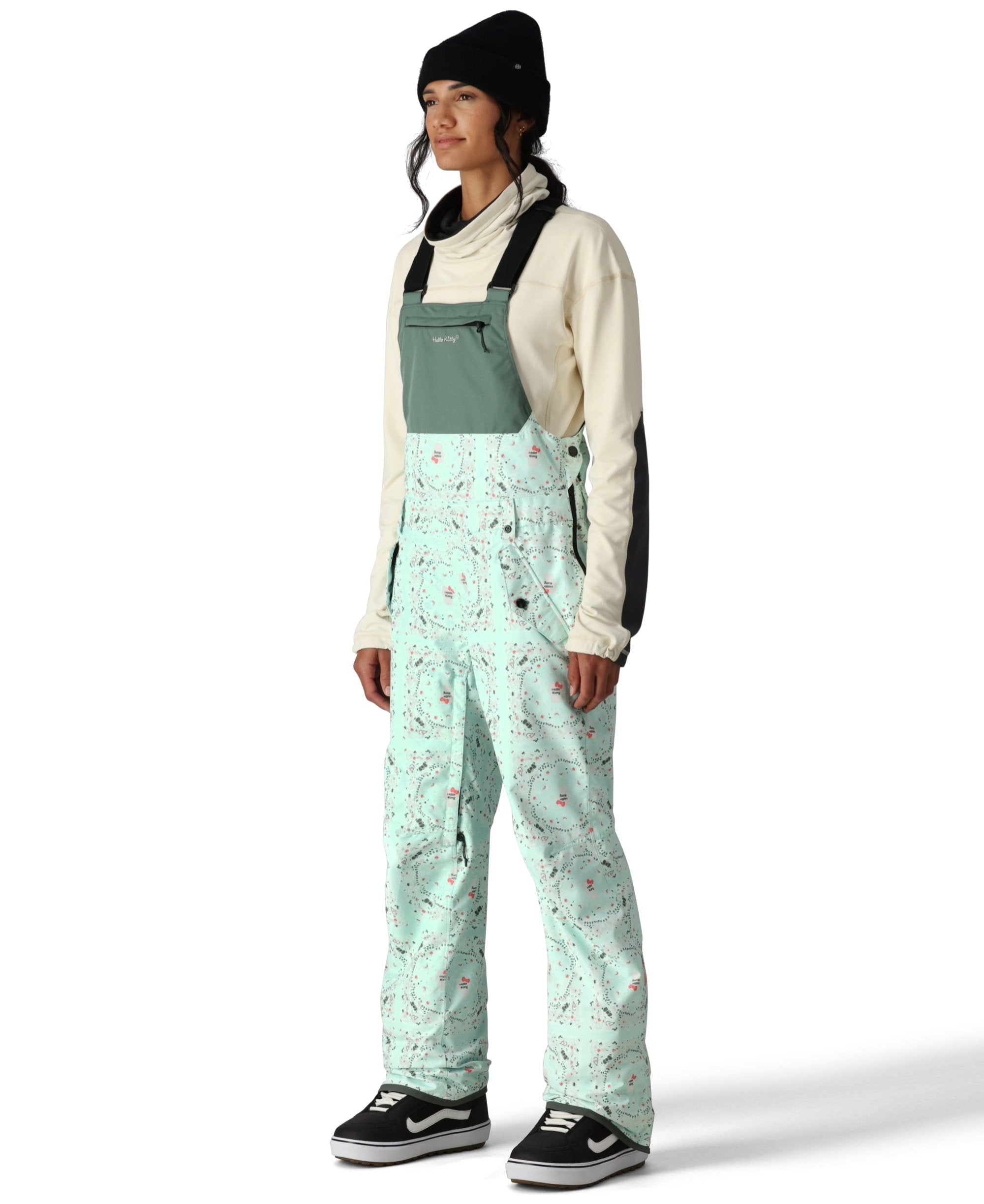 The 686 Women's Harper Shell Bib in light blue features a zip-in bib with an insulated hood, side zip pockets, and adjustable straps.