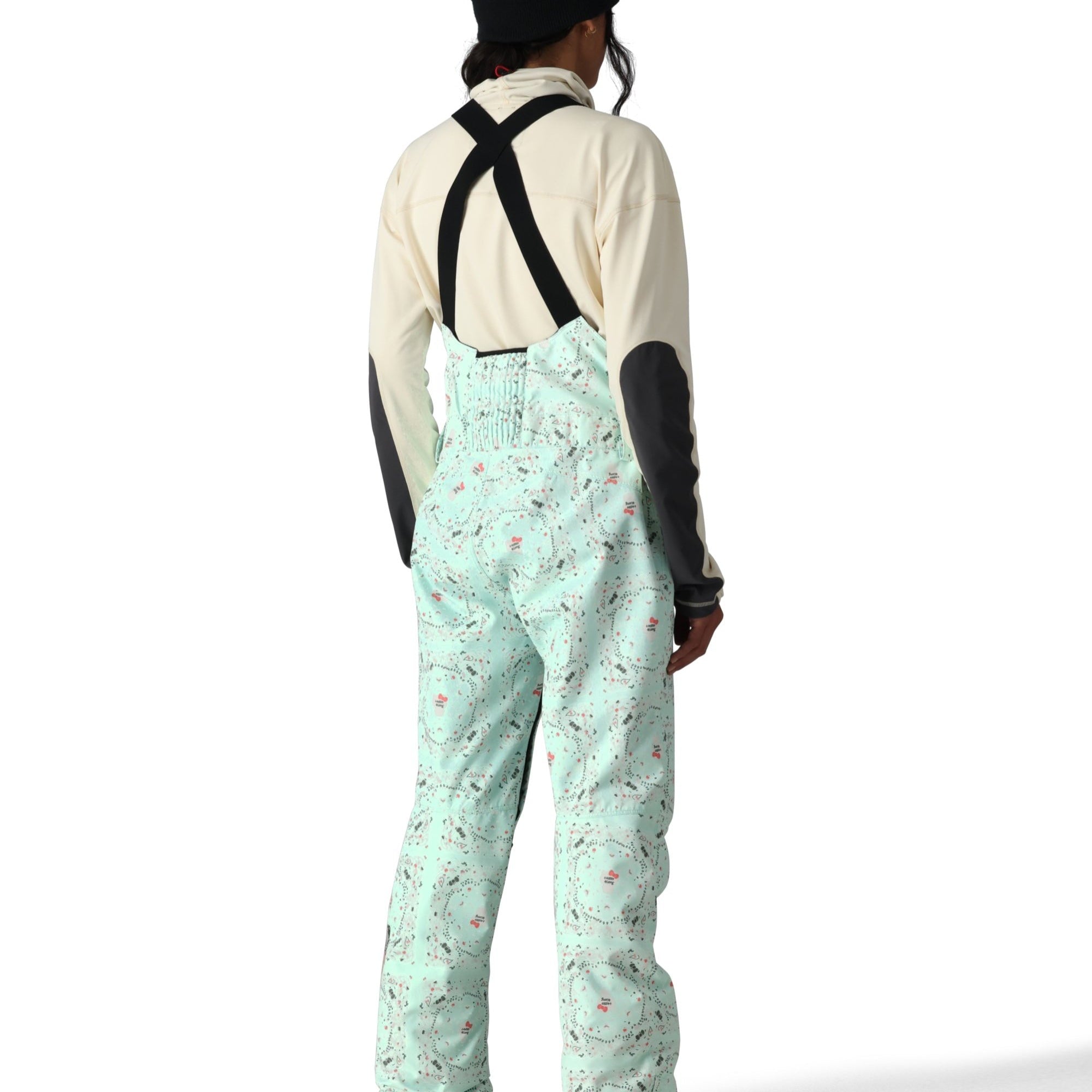 The 686 Harper Shell Bib pants are light green with a pattern of gray and pink ski trails on them.