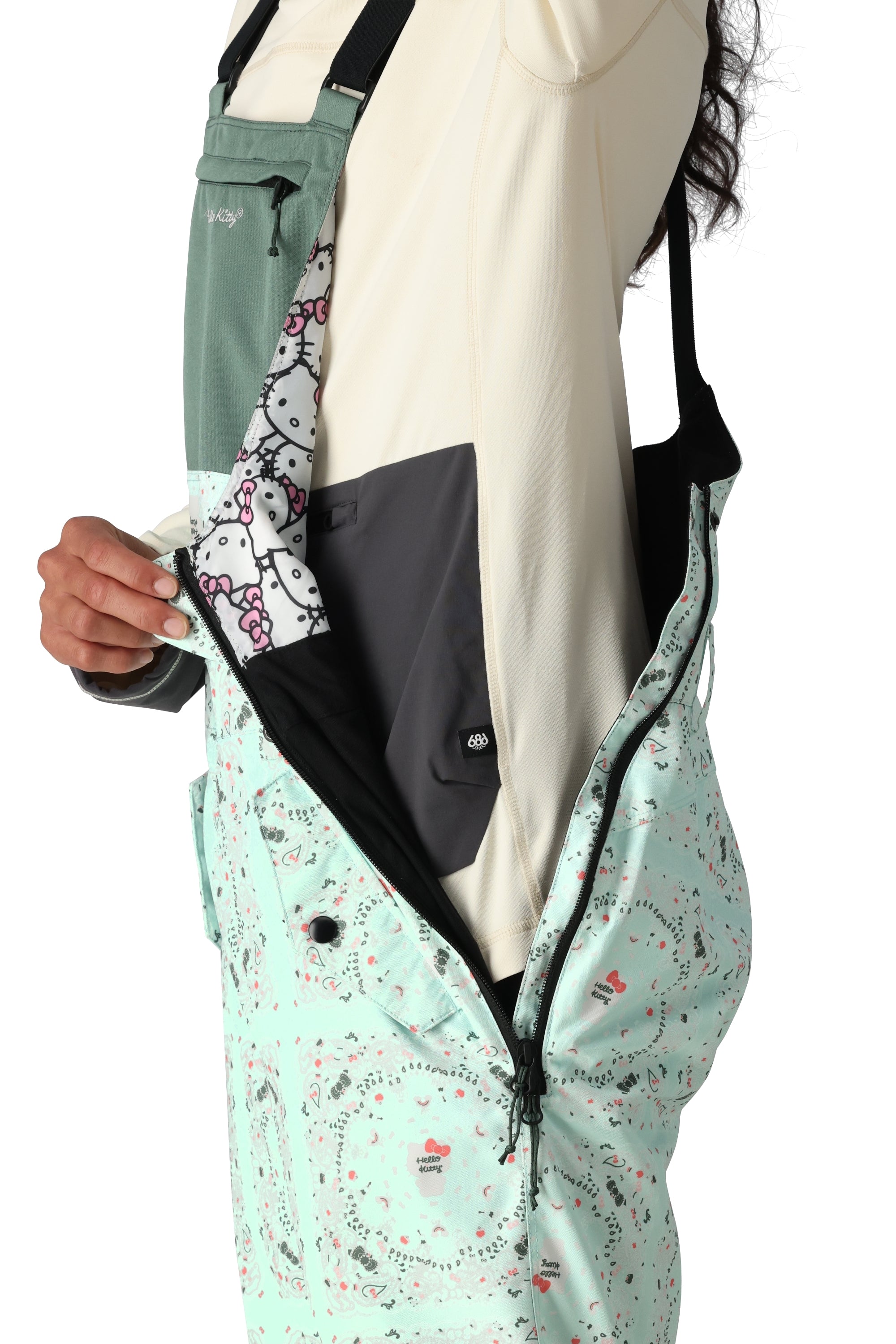 The 686 Women's Harper Shell Bib 2025 is primarily mint green with a pattern of small black and red shapes on its front view.