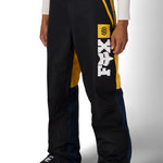 Men's shell pants, black with yellow accents, blue panel, and Fox logo on thigh