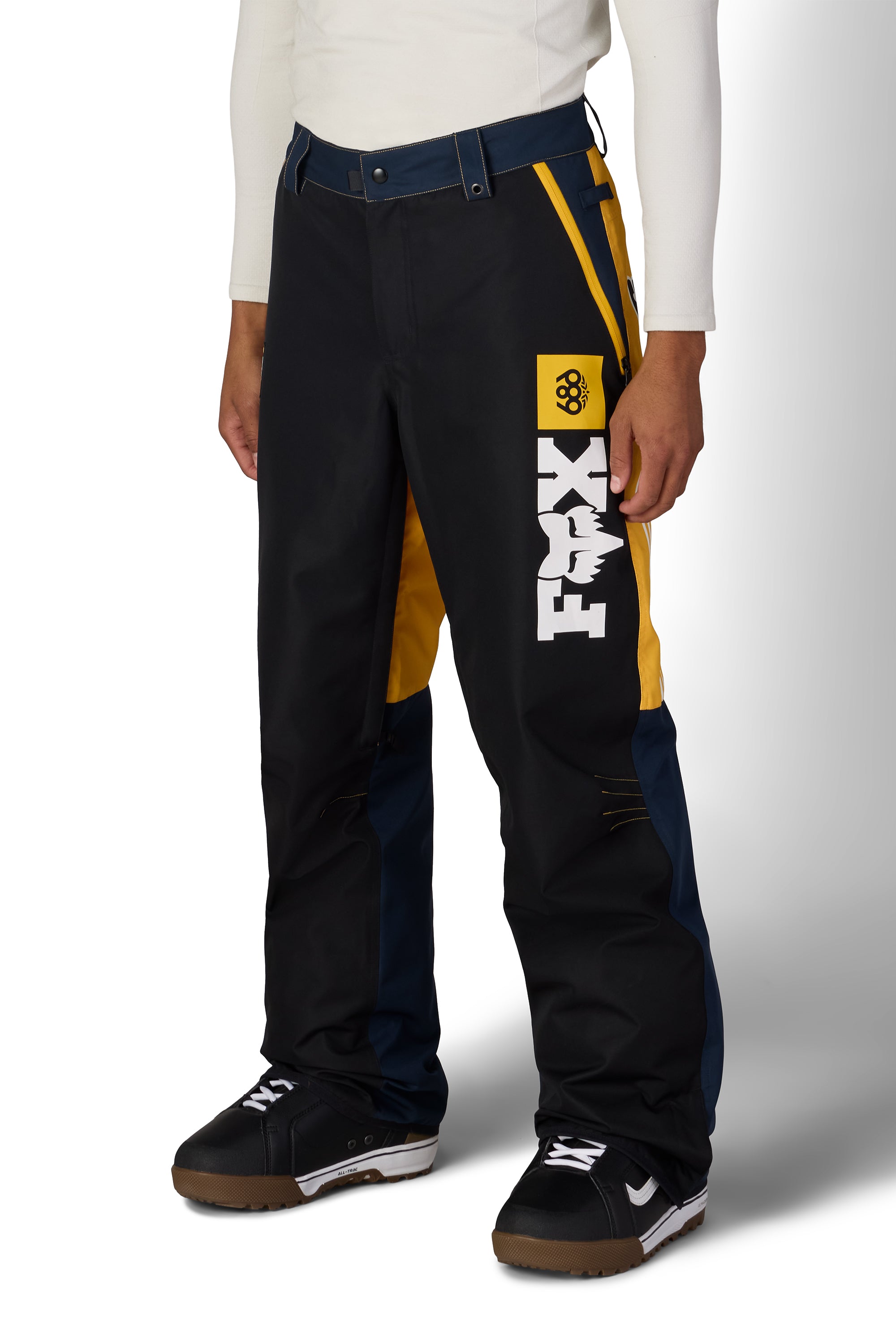 Men's shell pants, black with yellow accents, blue panel, and Fox logo on thigh