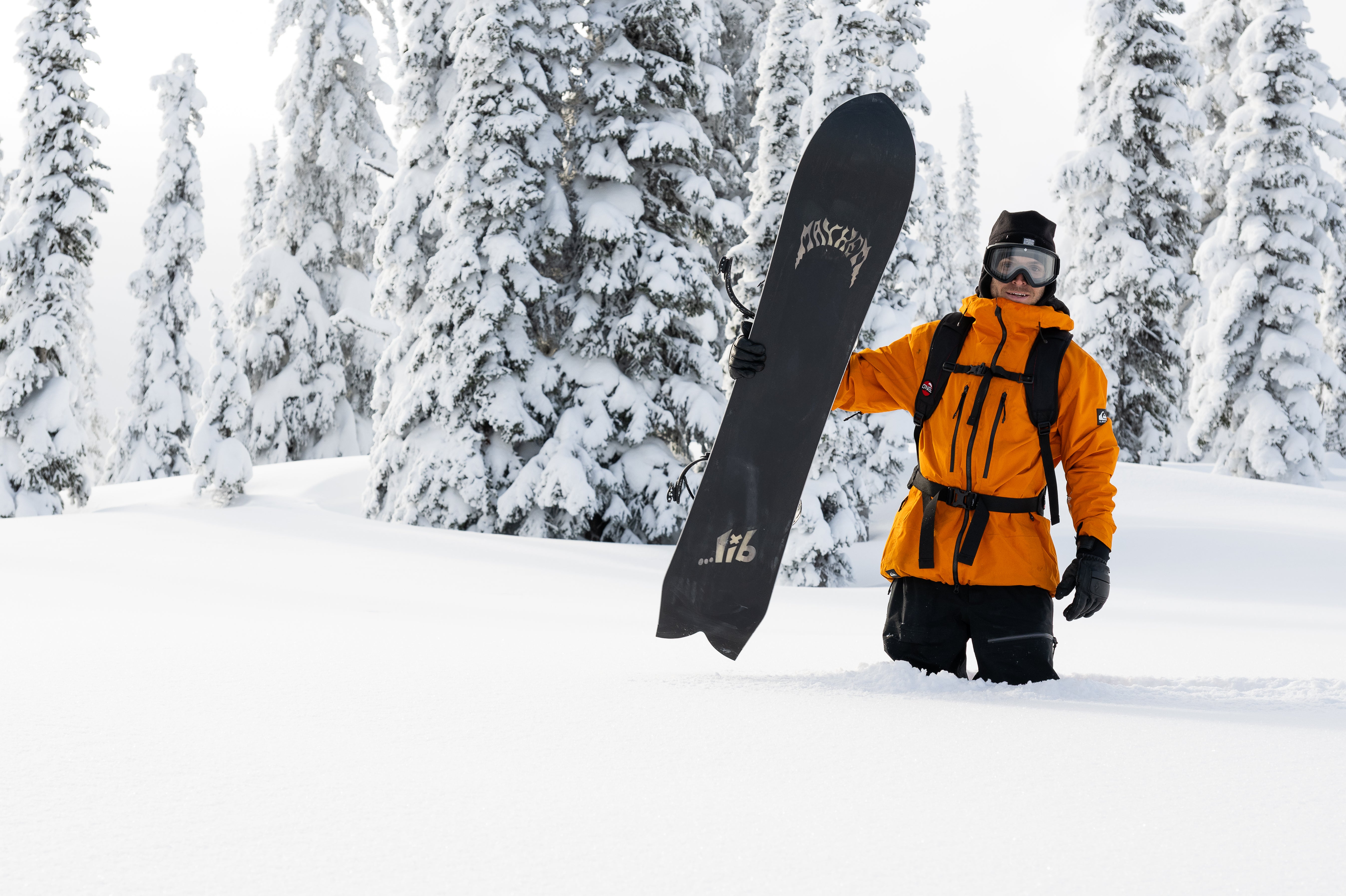 Lib Tech Mayhem Sweetfish snowboard upright outdoors, black deck with gold lightning graphics