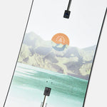 Burton Women's Family Tree Story Board B Grade Snowboard 2024 - A snowboard with a mountainous landscape and orange sun graphic on a white background.