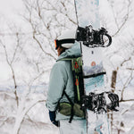 Burton Women's Family Tree Story Board B Grade Snowboard 2024 - A white snowboard with a blue and orange graphic design, featuring a mountain range and trees.