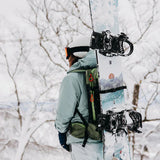 Burton Women's Family Tree Story Board B Grade Snowboard 2024 - A white snowboard with a blue and orange graphic design, featuring a mountain range and trees.