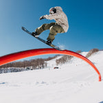 Burton Covert 2.0 2L Insulated Jacket 2025 - A man in a white snow jacket with brown and black accents is riding a snowboard on a halfpipe, performing a trick.