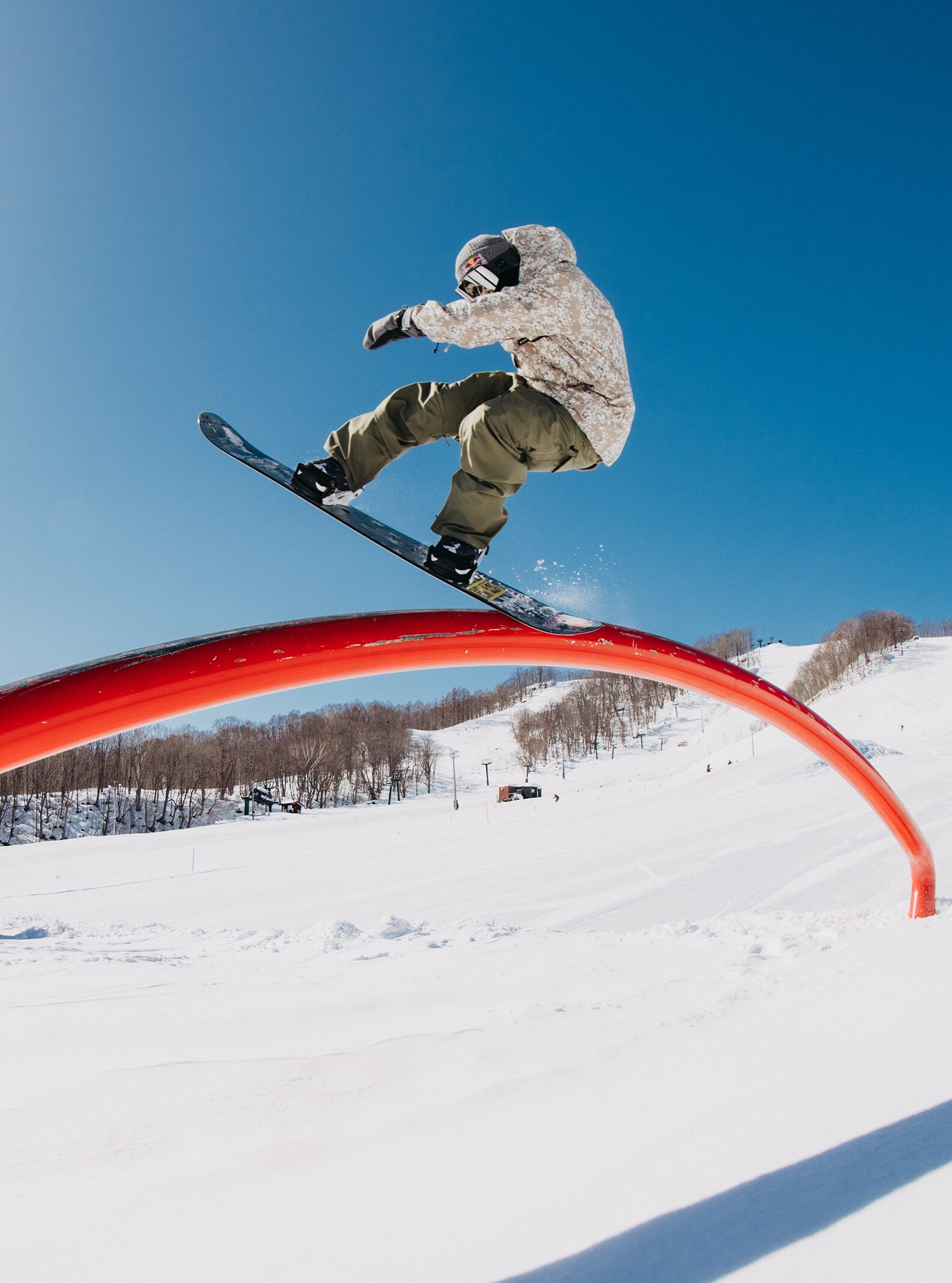 Burton Covert 2.0 2L Insulated Jacket 2025 - A man in a white snow jacket with brown and black accents is riding a snowboard on a halfpipe, performing a trick.