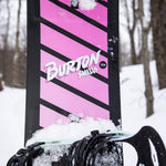 Burton Junior's Smalls Snowboard 2025 - A pink snowboard with black stripes and a black binding on top.