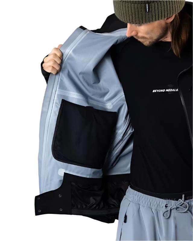 Beyond Medals Tech Shell Jacket 3L 2025 - A black jacket with a zippered chest pocket and reflective logo on the left breast.