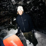 Beyond Medals Tech Shell Jacket 3L 2025 - A black jacket with a white logo on the chest and two zippered pockets on the front.