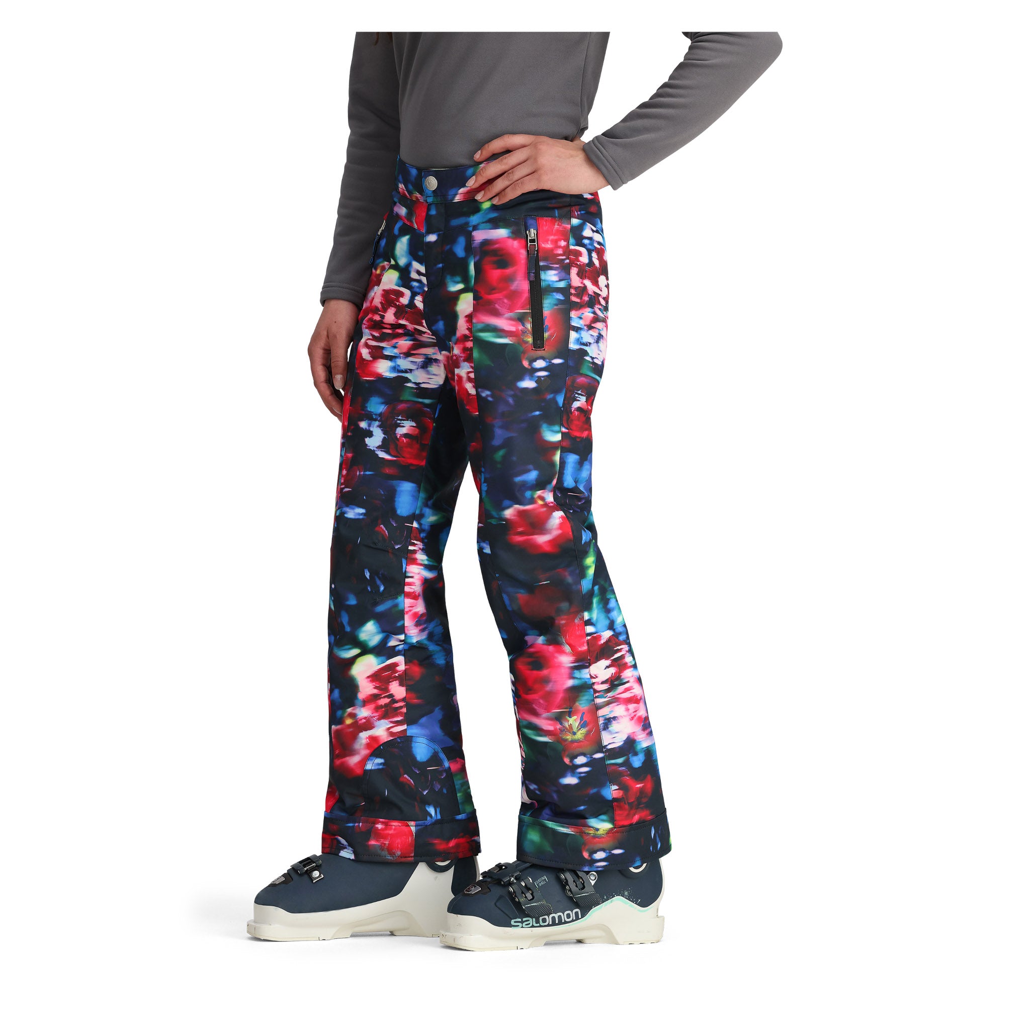 Obermeyer Girl's Brooke Print Pant 2025 - A pair of girls' snow pants with a colorful abstract print featuring red, blue, green, and white shapes on a black background.