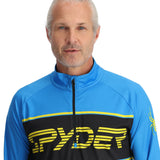 Spyder Men's Paramount 1/2 Zip Top 2025 - A blue and black zip-up top with a yellow logo on the chest.