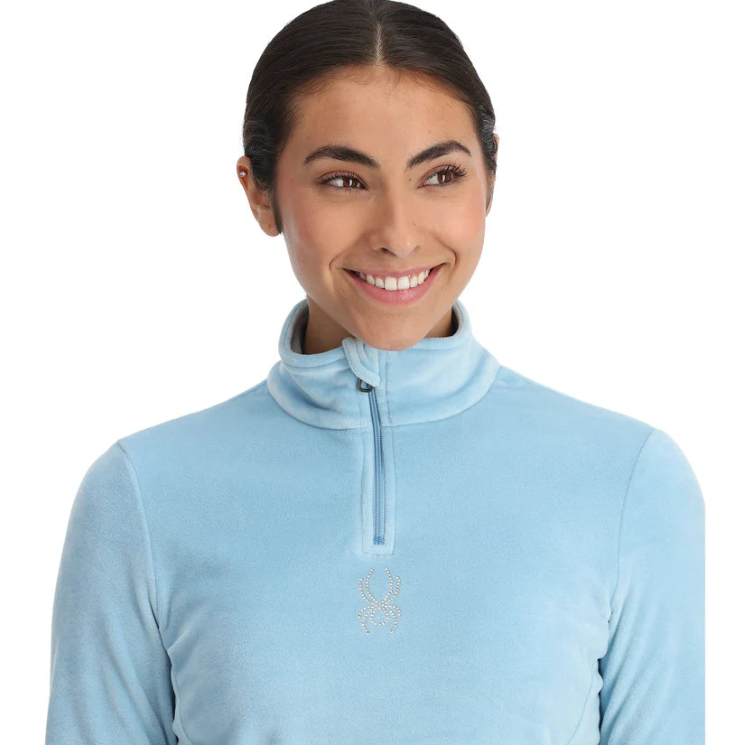 Spyder Women's Shimmer Bug 1/2 Zip Fleece 2025 - A light blue fleece jacket with a zipper and a small, sparkly bug logo on the chest.