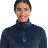 Spyder Women's Shimmer Bug 1/2 Zip Fleece 2025 - A woman wearing a blue fleece with a zipper and a shimmering pattern on the chest.
