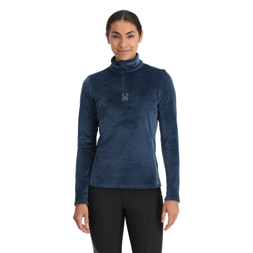 Spyder Women's Shimmer Bug 1/2 Zip Fleece 2025 - A woman wearing a blue fleece top with a zipper and a logo on the chest.