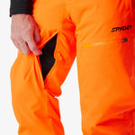 Insulated ski pants close-up with orange fabric, side pocket opening, and zipper detail