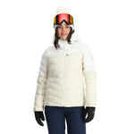 Spyder Women's Brisk Synthetic Down Jacket - A white down jacket with a high collar and zippered pockets, featuring a hood and a black zipper.