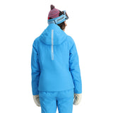 Spyder Women's Temerity Insulated Jacket 2025 - A woman wearing a blue ski jacket with a hood, standing in front of a white background.