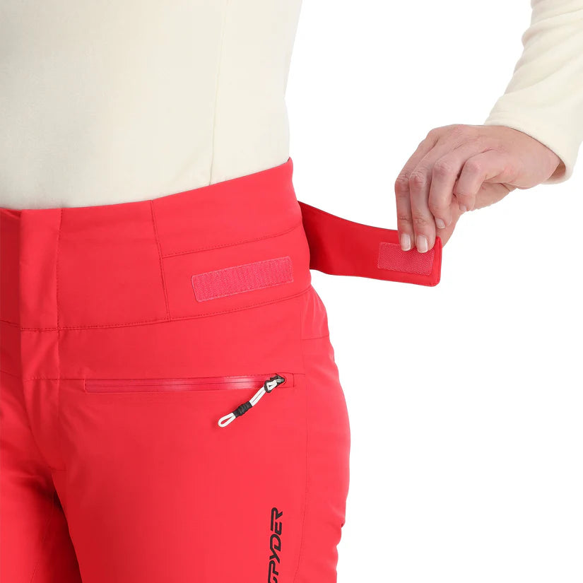 Spyder Women's Winner Insulated Pants 2025 - A pair of red ski pants with a zippered pocket on the right thigh and a black logo on the left leg.