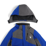 Spyder Boys' Turner Insulated Jacket 2025 - A blue and gray insulated jacket with a hood, featuring a white spider logo on the left chest.