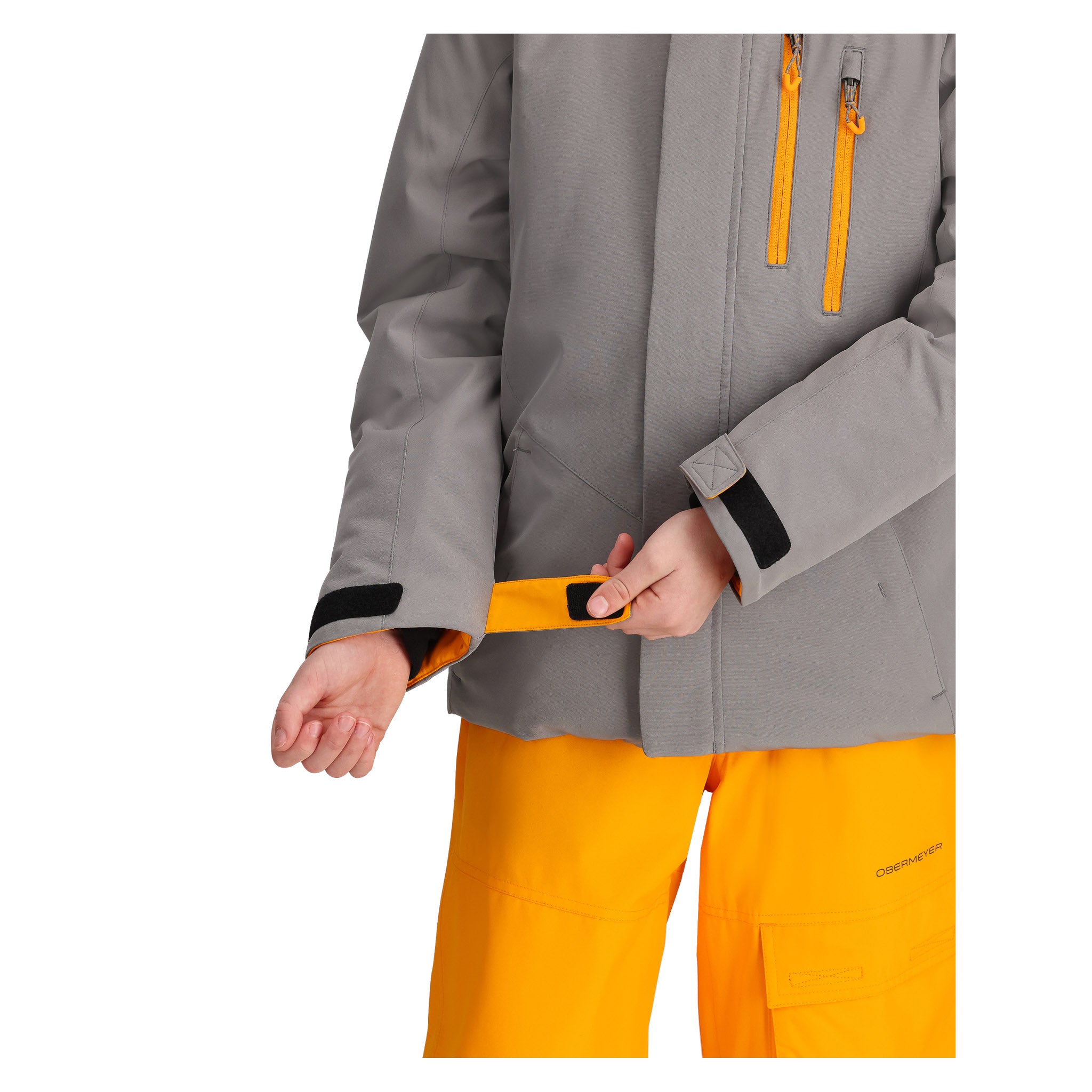 Obermeyer Junior's Insulated Gentleman's Jacket - A grey jacket with a black zipper and orange accents on the cuffs, worn by an unseen model.