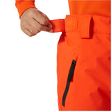 Helly Hansen Junior's Legendary Insulated Pant 2025 - A pair of bright orange insulated ski pants with a black zipper on the side pocket.