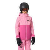 Helly Hansen Junior's Traverse Insulated Jacket 2025 - A young child wearing a pink and light-pink jacket with a hood, black gloves, and a black helmet.
