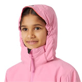 Helly Hansen Junior's Traverse Insulated Jacket 2025 - A young girl wearing a pink jacket with a hood, smiling directly at the camera.