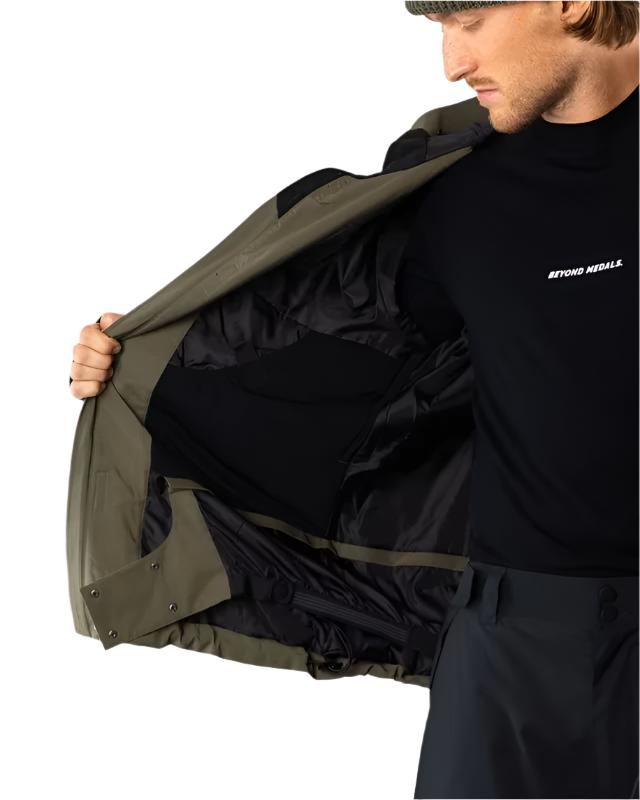 Beyond Medals Cargo Shell 2L Jacket 2025 - A dark olive green jacket with a black zipper and two zippered pockets on the front.