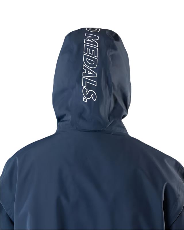 Beyond Medals The Jacket Shell 2025 - A navy blue jacket with a white logo on the left chest and a zipper running down the front.