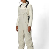 Women’s insulated bib overalls in off-white with front pockets, suspenders, and ankle cuffs.