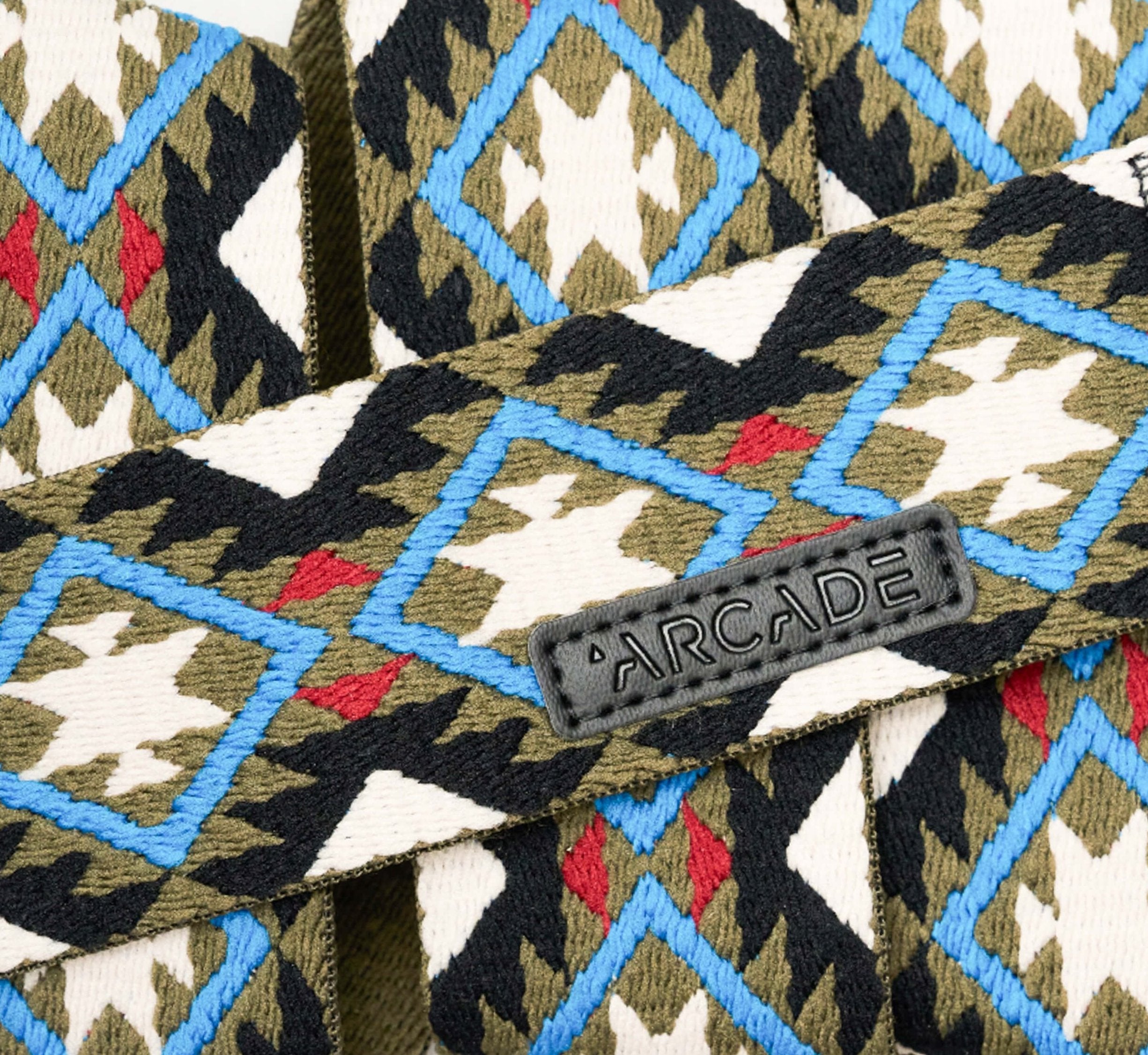 Arcade Twilight Belt 2025 - A black belt with a repeating pattern of white, blue, and red diamonds on a green background.