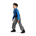 Obermeyer Junior's Warp Insulated Bib Pant 2025 - A pair of black and grey snow pants with a repeating pattern of skiers, trees, and mountains.
