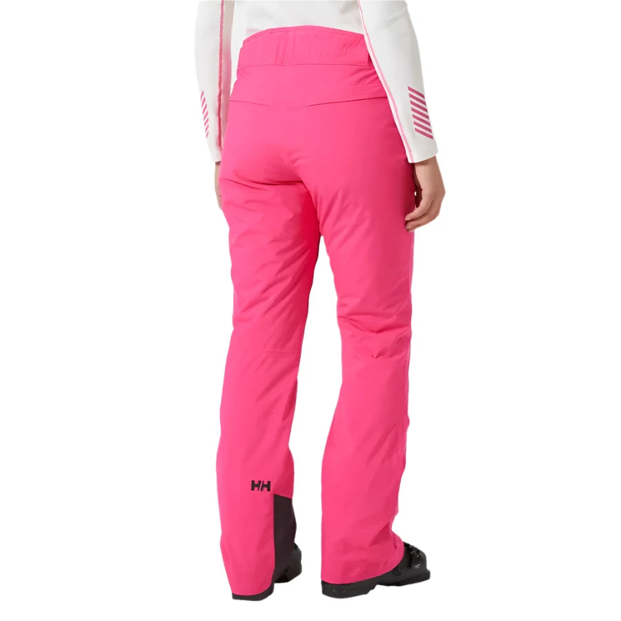Helly Hansen Women's Legendary Insulated Pant 2025 - A pair of bright pink snow pants with a black logo on the left leg, featuring a zippered pocket and a small black tag near the waistband.