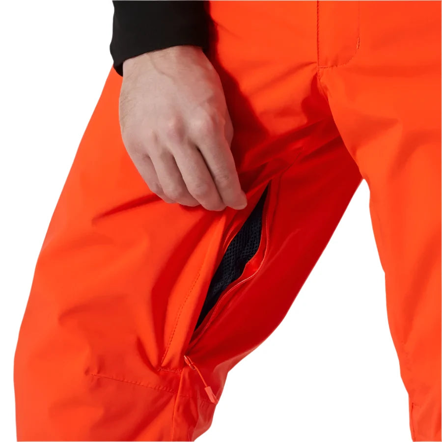 Hally Hansen Men's Legendary Insulated Pant - A pair of bright orange insulated pants with a zippered fly and two front pockets, featuring a black textured pattern on the inner thigh area.