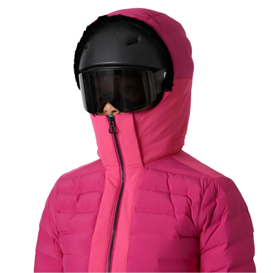 Helly Hansen Women's Avanti Insulated Jacket - A woman wearing a black helmet with a dark visor and a pink ski jacket with a high collar, zipped up to her chin.