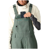 The 686 Women's Black Magic Insulated Bib 2024 is showcased in a black color with an adjustable waist belt and buckle closure.