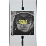 Burton Women's Story Board Snowboard - A black-and-white image of a woman wearing sunglasses and a hat, with the words "STORY BOARD" in yellow across her glasses.