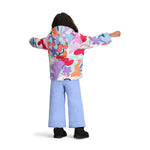 Obermeyer Junior's Ashor Insulated Jacket - A pastel blue jacket with a white snowflake pattern and a hood, worn by a young girl with long brown hair.