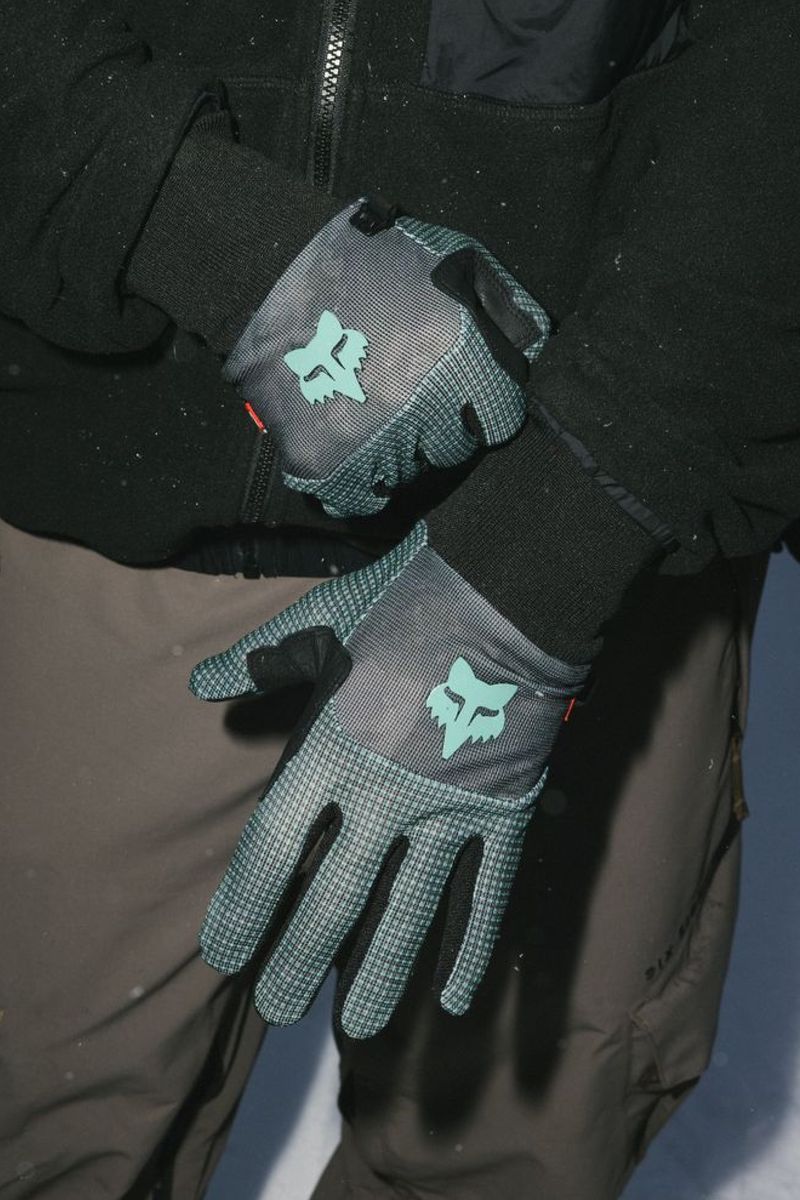Teal-and-black ski gloves with teal bull logo patch and grippy fingertip design