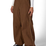 Brown shell pants with belt loops, side pockets, and relaxed wide legs