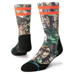 XTRA CREW C SOCK 2023 - A pair of crew socks with a repeating pattern of green and brown leaves on a tan background, featuring two orange stripes at the top.